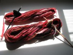 Red, brown, and white spun yarn with two drop spindles thumbnail.