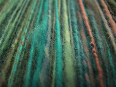 Teal, pink, and green spun yarn close up.
