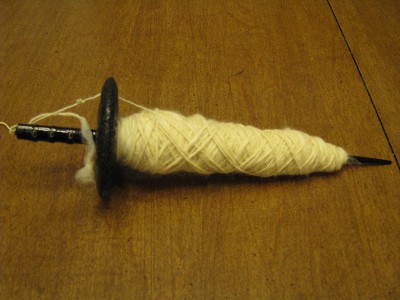 Undyed spun yarn on black drop spindle.