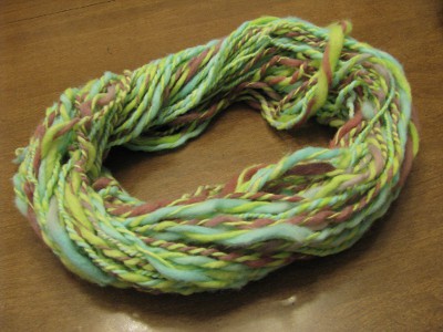 Blue and violet dyed spun yarn plied with bright green spun yarn.